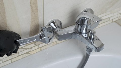Plumber fixing repairing a leaky shower Bathtub water tap  faucet by wrench tool, Bathroom shower plumbing fix mount DIY concept 