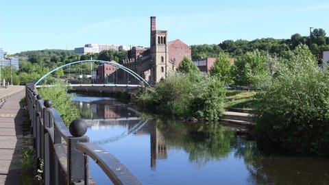 Sheffield, South Yorkshire, England, UK - May 29th 2020 -  Video of traditional red brick houses along the waterfront and River Don in Sheffield. Upper Don Walk. Arch bridge. City centre. Sunny Day.