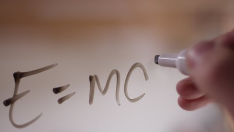 "E=mc2" written on clear plexiglass with a dry erase marker