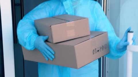 close-up, Delivery of parcels with medical equipment or drugs to hospital during coronavirus outbreak. Courier, in protective suit, is handing cardboard boxes to nurse. Cargo delivery service