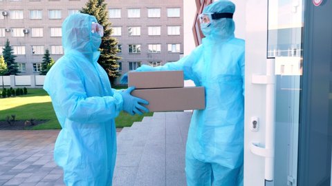 Delivery of parcel with medical equipment or drugs to hospital during coronavirus outbreak. Courier, in protective suit, is handing cardboard box to nurse. Cargo delivery service during quarantine.
