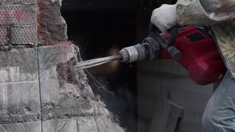 Close-up. Worker breaks the wall with a perforator. Slow motion.