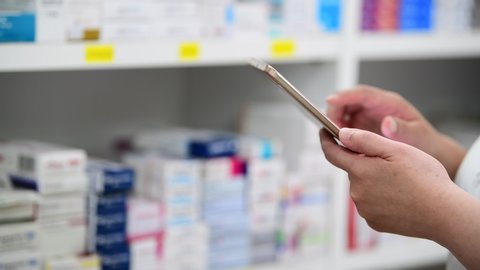 Pharmacist holding computer tablet Inspecting medicine stock in pharmacy drugstore.