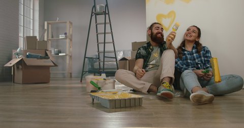 Newlywed caucasian couple are relaxing during renovation of their new home, doing a highfive and positively smiling - new life, mortgage concept 4k footage