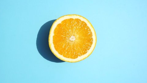 Orange rotating on the sunlight on a colored blue background. Fruit juices, relaxation, tropics and relaxation concept.