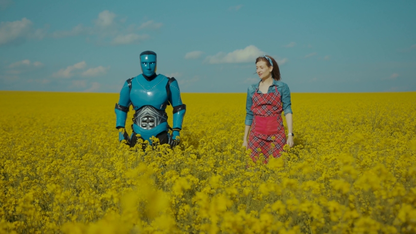 Funny cyborg android robot dancing in couple with young cheerful pretty woman romantic dance on yellow flower field outside. Human and robots friendship. Royalty-Free Stock Footage #1054782989