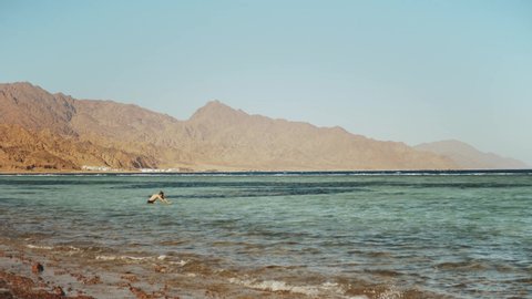 Man snorkeling in red sea, Beautiful landscape of blue sea and clear sky, waves in the sea and mountains on horizon Egypt, Dahab, 4k