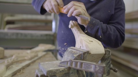Carpenter carves wood using chisel