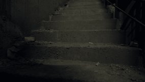 Blurred outline of a man climbing a flight of dark shadowy steps passing the camera for a thriller or mystery concept