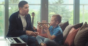 Father and son play trumpet at home. Dad teaches child to play musical instruments. Music hobby, Create, Dream, learning own songs. SHARE THE LOVE, play our game. 4K video.