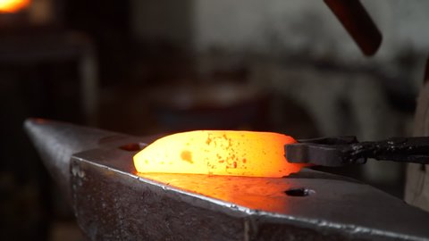 Closeup of Man Hitting a Hot Red Metal with a Hummer. Blacksmith Forging Red-hot Blade of Knife in Smithy. Slow Motion