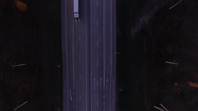 Trucks and cars go along the highway. Top view of the highway at sunset in the evening. Cars drive on an asphalt road. Road junction, autobahn. Drone video