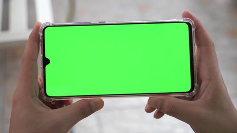 Close up Horizontal hands holding smartphone with green screen. Green screen mobile phone with chroma key. Perfect for product placement.