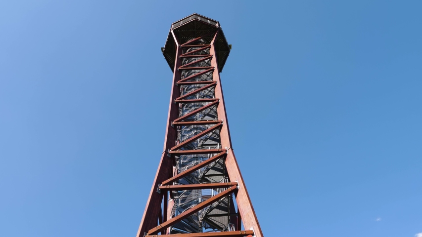 Close up tilt down of lookout tower in the woods on a sunny day in summer.
