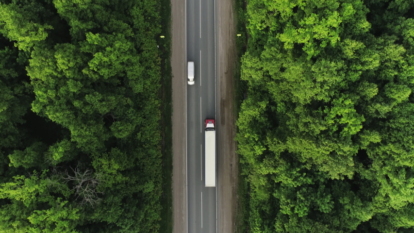 One Semi Truck with white trailer and cab driving / traveling alone on dense flat forest asphalt straight empty road, highway top down view follow vehicle aerial footage / Freeway trucks traffic Royalty-Free Stock Footage #1054808027