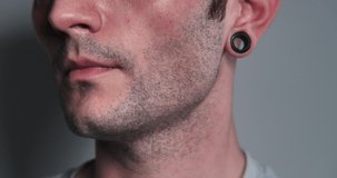 Round earrings of black tunnels in the ears close-up. Tunnels in the ears as a way of self-expression and lifestyle of a young man. Young man socializing.