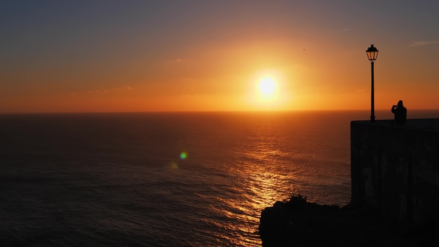 Toutist enjoys the view from the Miradouro do Nazare at sunset. Nazare canion viewpoint. Portugal
