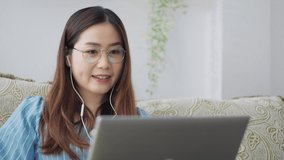 Serious Asian woman distance student online wear headphone conferencing on laptop communicate by video call explain course help e learning computer education concept. Distancing working online at home