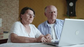 elderly wife and her old husband complain of feeling unwell and pressure during an online consultation with doctor, using webcam on laptop while sitting at table in room