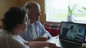 62 medicine online, old man and woman consult doctor online about telemedicine with help of video call while sitting at table with laptop in room