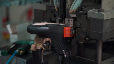 professional shoemaker working with automatic machinery at shoe factory