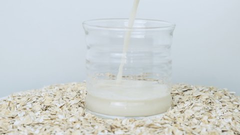 Oat milk in transparent cup, poured into glass