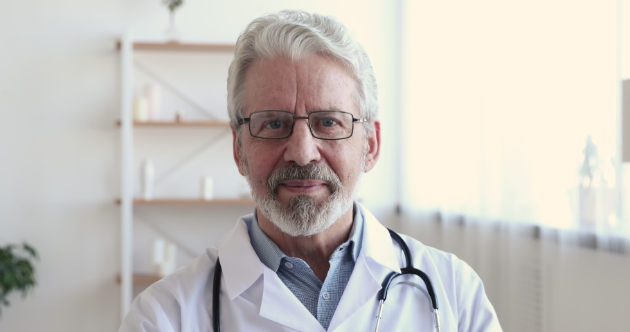Close up head shot smiling middle aged senior head doctor in white coat with stethoscope on neck looking at camera. Portrait of confident skilled happy general practitioner physician in eyeglasses. Royalty-Free Stock Footage #1054824572
