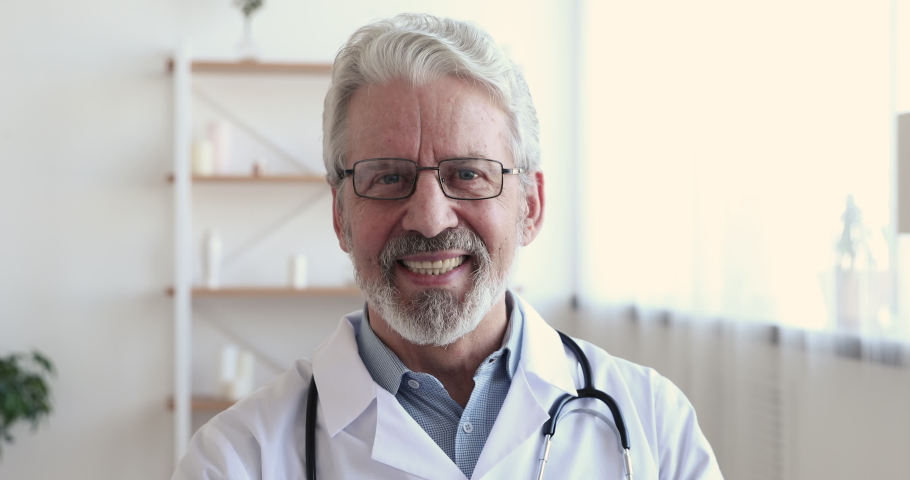 Close up head shot smiling middle aged senior head doctor in white coat with stethoscope on neck looking at camera. Portrait of confident skilled happy general practitioner physician in eyeglasses. | Shutterstock HD Video #1054824572