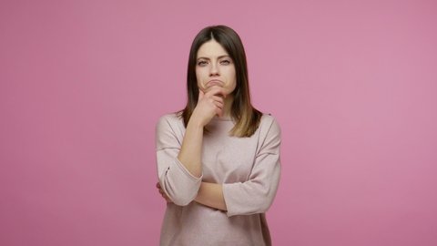 Pensive brunette woman rubbing chin while solving serious problem in mind, nodding approvingly, thinking over smart idea, pondering and musing answer. indoor studio shot isolated on pink background