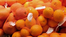 4k Footage ripe orange fruits in food aisle at supermarket. Buy natural fruit for healthy nutrition. Video of oranges and mandarins packed in transparent packaging in foods market.