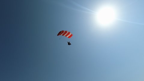 Extreme skydiver flying against a clear blue sky, sunbeam shines into camera