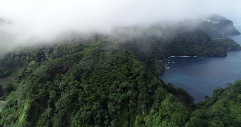 Drone on top of Cocos island in Clouds moving on rainforest ocean in background