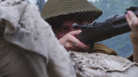 World War 1 British soldier repeatedly firing bolt action rifle on the battlefield. Smoke in the air (Shot on RED) 4K