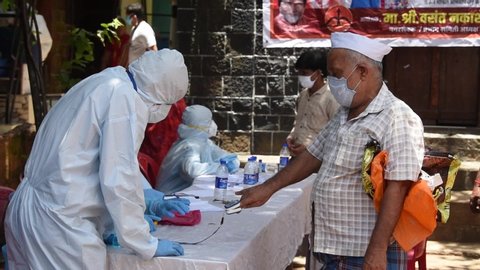 MUMBAI/INDIA- JUNE 10, 2020: Medical staff wearing protective gear monitor people’s body temperature during COVID-19 testing drive at Dharavi slum.