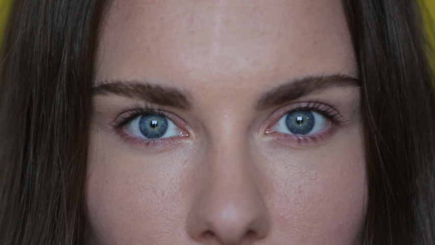 Woman open blue eyes. Close up of female face with wide blue eyes. Brunette woman portrait. Beautiful female macro. Attractive eyes looking camera. Perfect model face | Shutterstock HD Video #1054844207