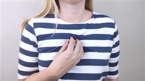 A woman grabs his chest in the region of the heart. Heart attack or chest pain. The concept of heart disease and its pain manifestations.