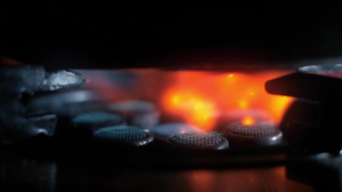Gas stove being turned on in the dark background, Close up of gas is switching on, appearing blue flame.