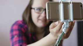 Close up of a phone on a selfie stick. Woman blogger recording video.