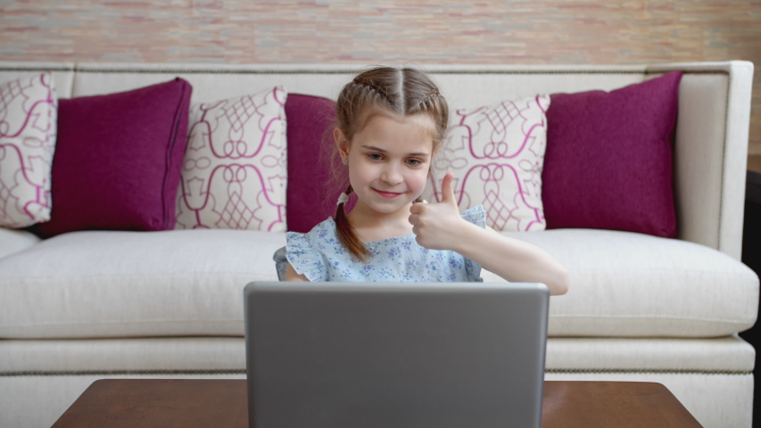 Little girl having a video call at home. Child looking to camera, smiling, waving hand. Online education concept. Communication via internet distantly. Chatting with teacher using laptop | Shutterstock HD Video #1054856324