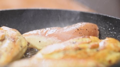 Cooking of chicken breast in frying pan.