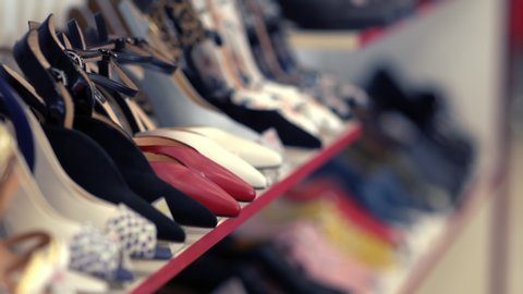hand of a woman shopper selecting stylish high heeled shoes off the shelf in a boutique store before replacing them and moving on to a different style