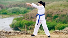 Young woman practicing martial arts outdoors overlooking a valley and river in a healthy active lifestyle concept