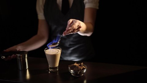 Bartender preparing Baileys comet cocktail, setting it on fire using culinary torch