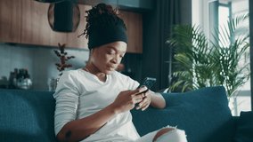 Close up relaxed afro american woman hold use smart phone watching social media sit on sofa technology young smartphone shopping online sale slow motion
