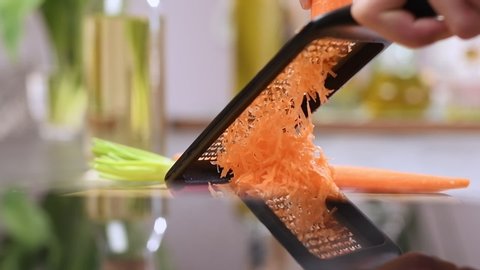 Grating carrot with a grater in the kitchen.