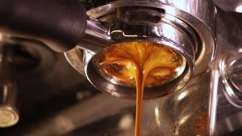 Closeup of pouring coffee stream from professional machine through the bottomless portafilter type with beautiful tiger crema of coffee. Flowing fresh ground coffee concept