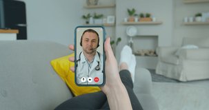 Woman checks possible symptoms with professional physician, using online video chat. Young girl sick at home using smartphone to talk to her doctor via video conference medical app.