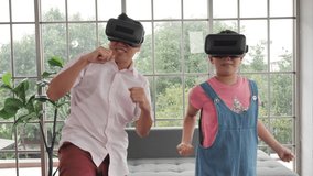 Asian family Father and daughter wearing virtual reality goggles are boxing fun video games in home. Holiday activities, Stay at home. Slow motion