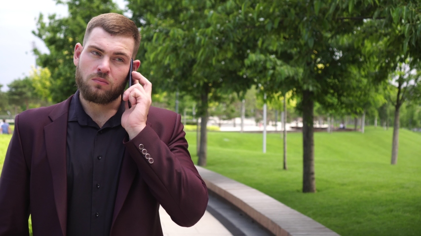 Male businessman in a business suit talking on the phone outdoors