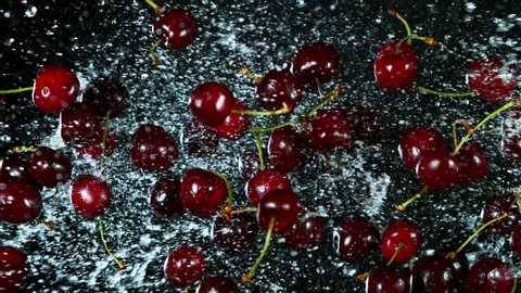 Super Slow Motion Shot of Flying Fresh Cherries and Water Side Splash on Black Background at 1000fps.
